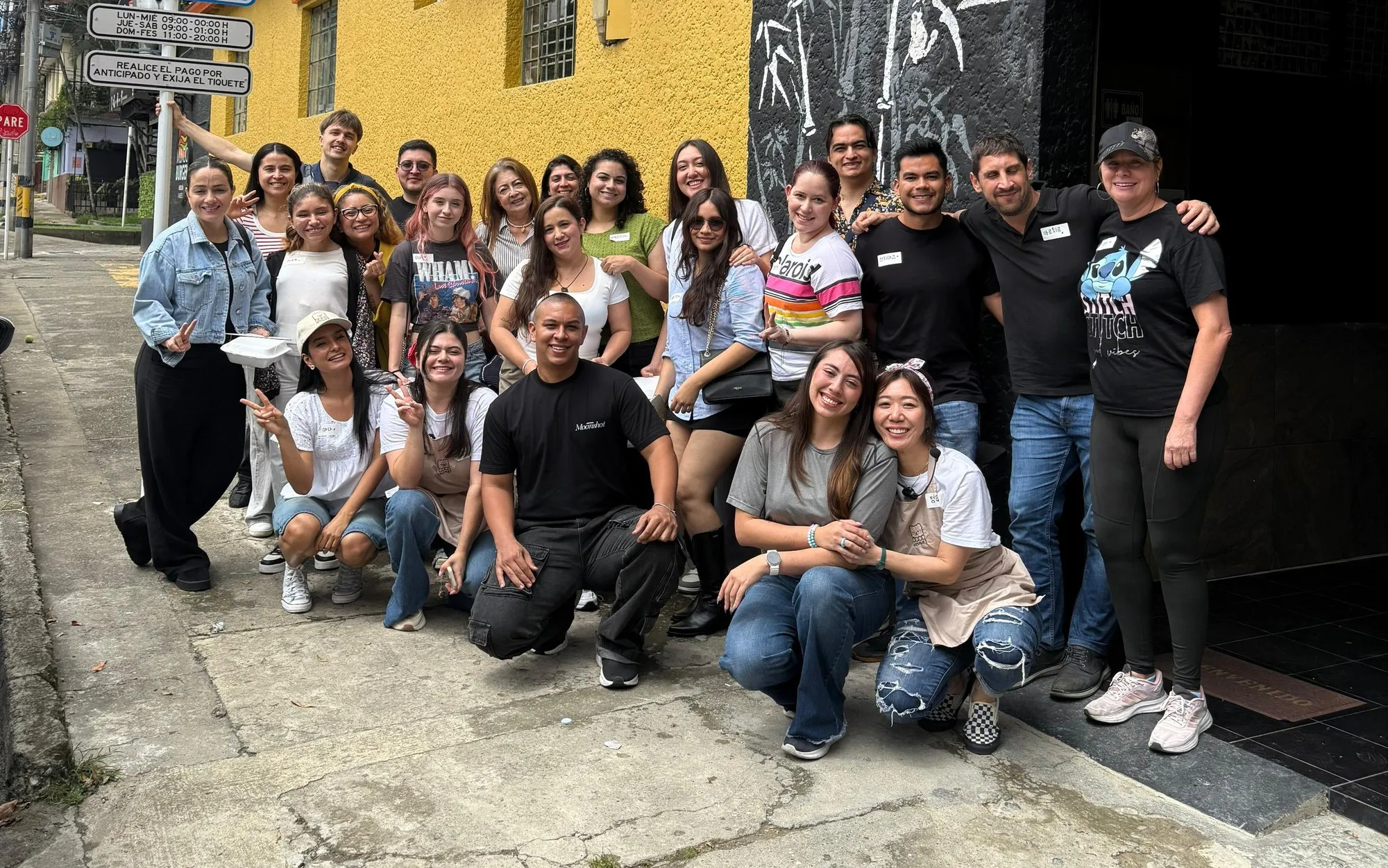 Foto de grupo de los asistentes en la calle, frente a una fachada amarilla.
